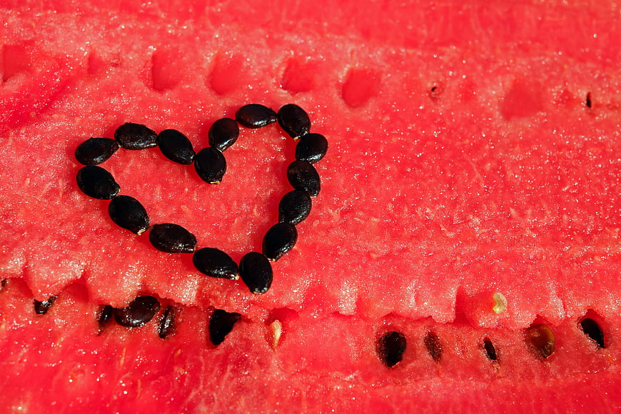 Watermelon seeds arranged in a heart shape on red fruit