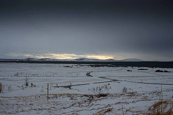 Snowy Winter Landscape with Distant Mountains and Overcast Sky
