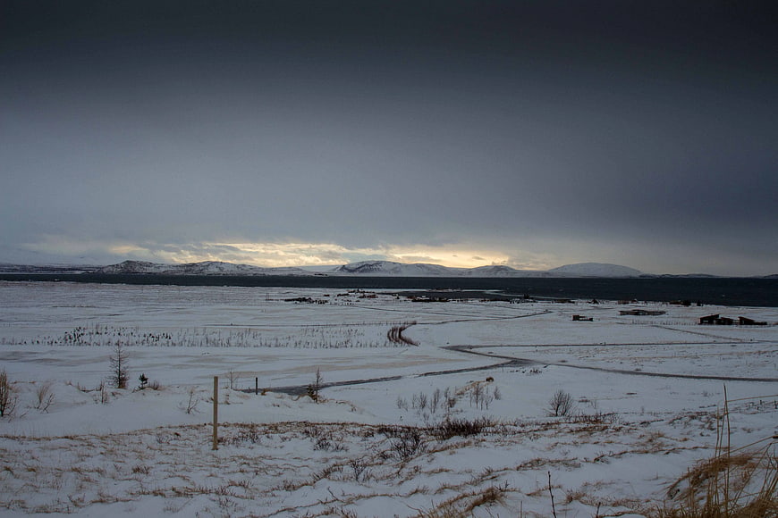 Snowy Winter Landscape with Distant Mountains and Overcast Sky