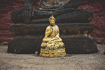 Golden Buddha Statue in Front of Ancient Stone Sculpture