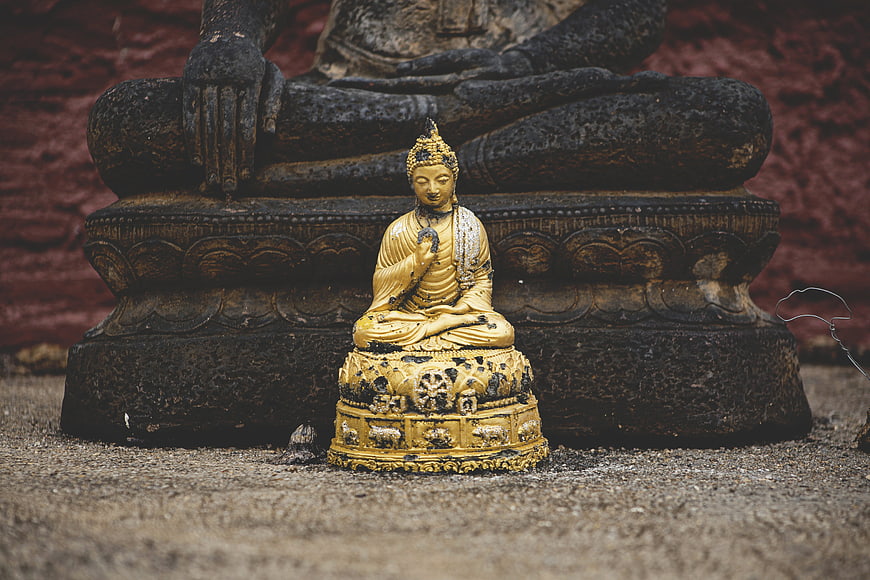 Golden Buddha Statue in Front of Ancient Stone Sculpture