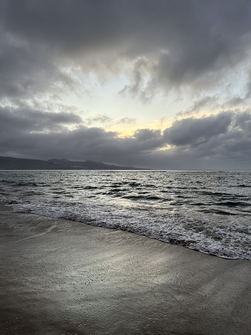 Dramatic cloudy seascape with waves on sandy beach at dusk