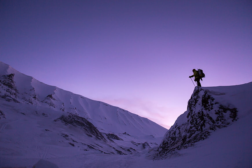 Silhouette of Mountaineer on Snowy Peak at Twilight
