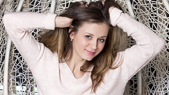 Young Woman In Pink Sweater With Hands In Hair