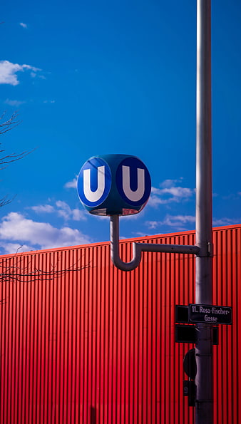 Blue U-Bahn Sign Against Red Corrugated Wall and Sky