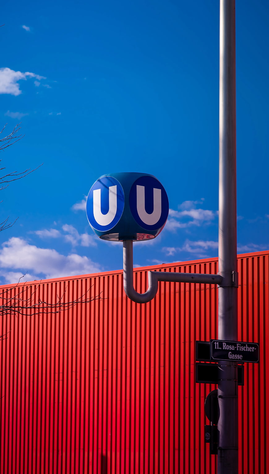 Blue U-Bahn Sign Against Red Corrugated Wall and Sky