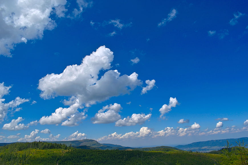 Vibrant Blue Sky with Fluffy White Clouds Over Green Hills