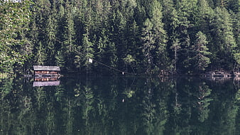 Serene wooden cabin on a lake with forest reflection