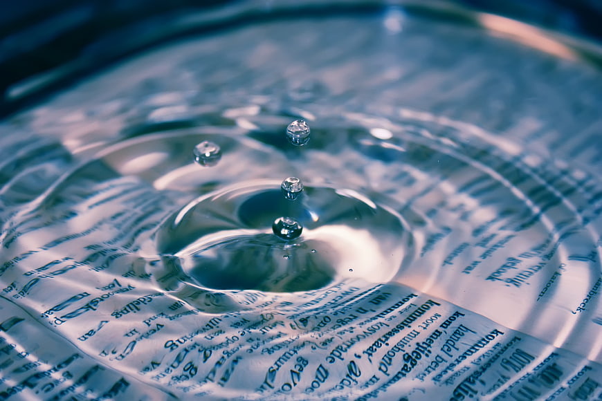 Macro water droplet splash on newspaper text