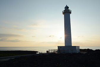 White Lighthouse Silhouette at Sunset Over Ocean