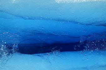 Underwater view of blue ice cave with air bubbles