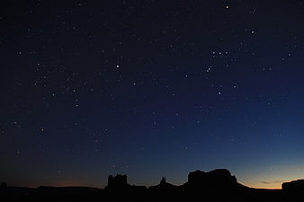 Silhouette of desert rock formations under a starry night sky
