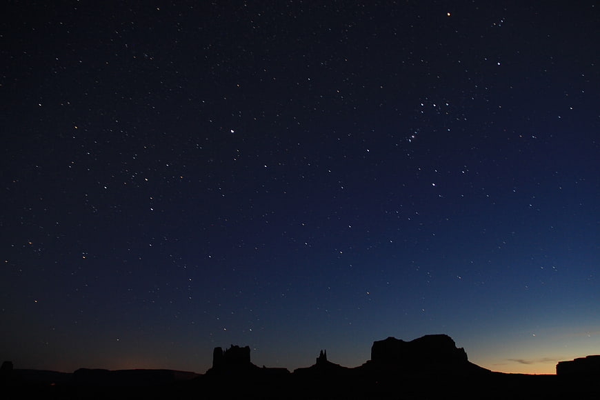Silhouette of desert rock formations under a starry night sky