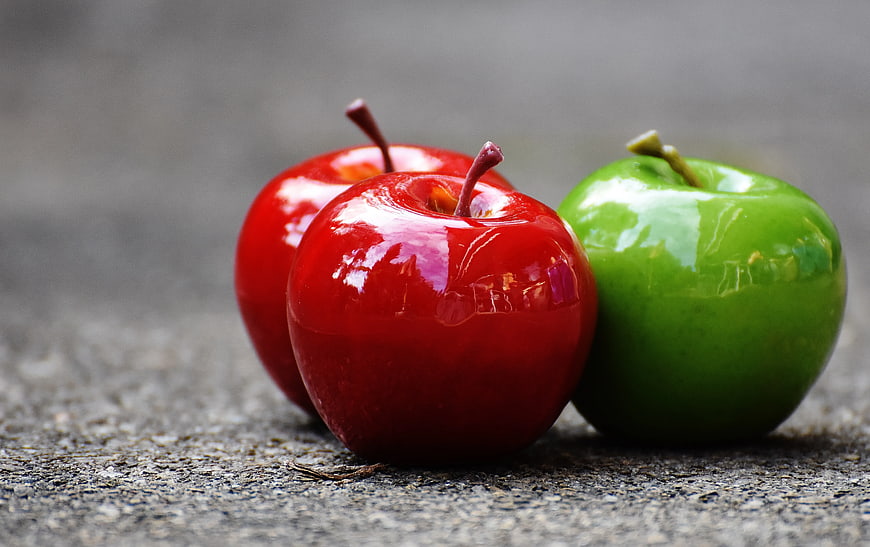 Three shiny red and green apples on textured surface