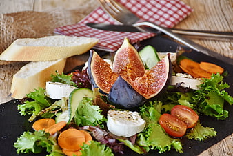 Fresh fig and goat cheese salad with baguette on slate