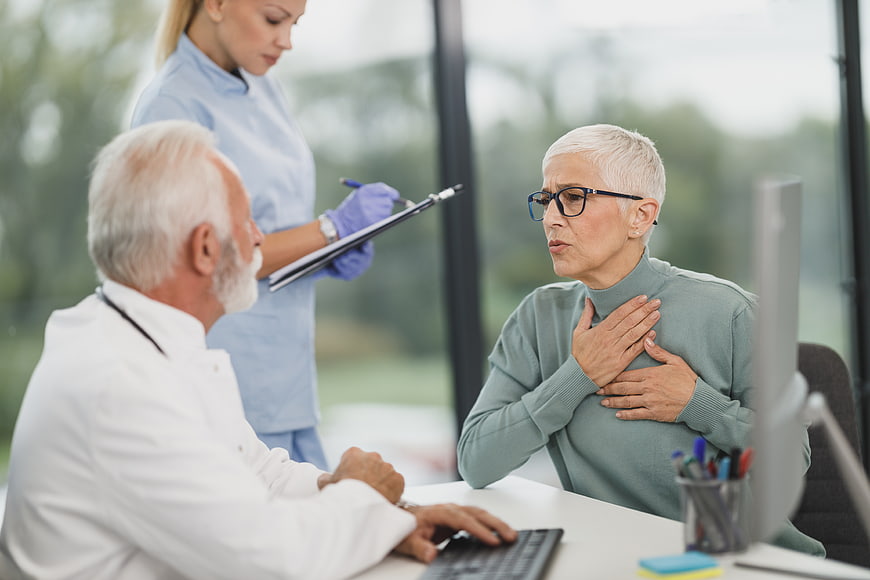 Senior woman clutching chest during doctor consultation