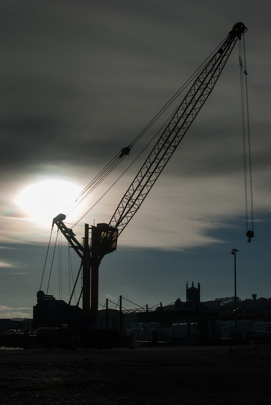 Silhouette of large crane against dramatic cloudy sky