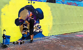 Street artist painting colorful graffiti mural on wall