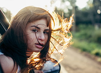 Young woman with windblown hair in golden sunlight