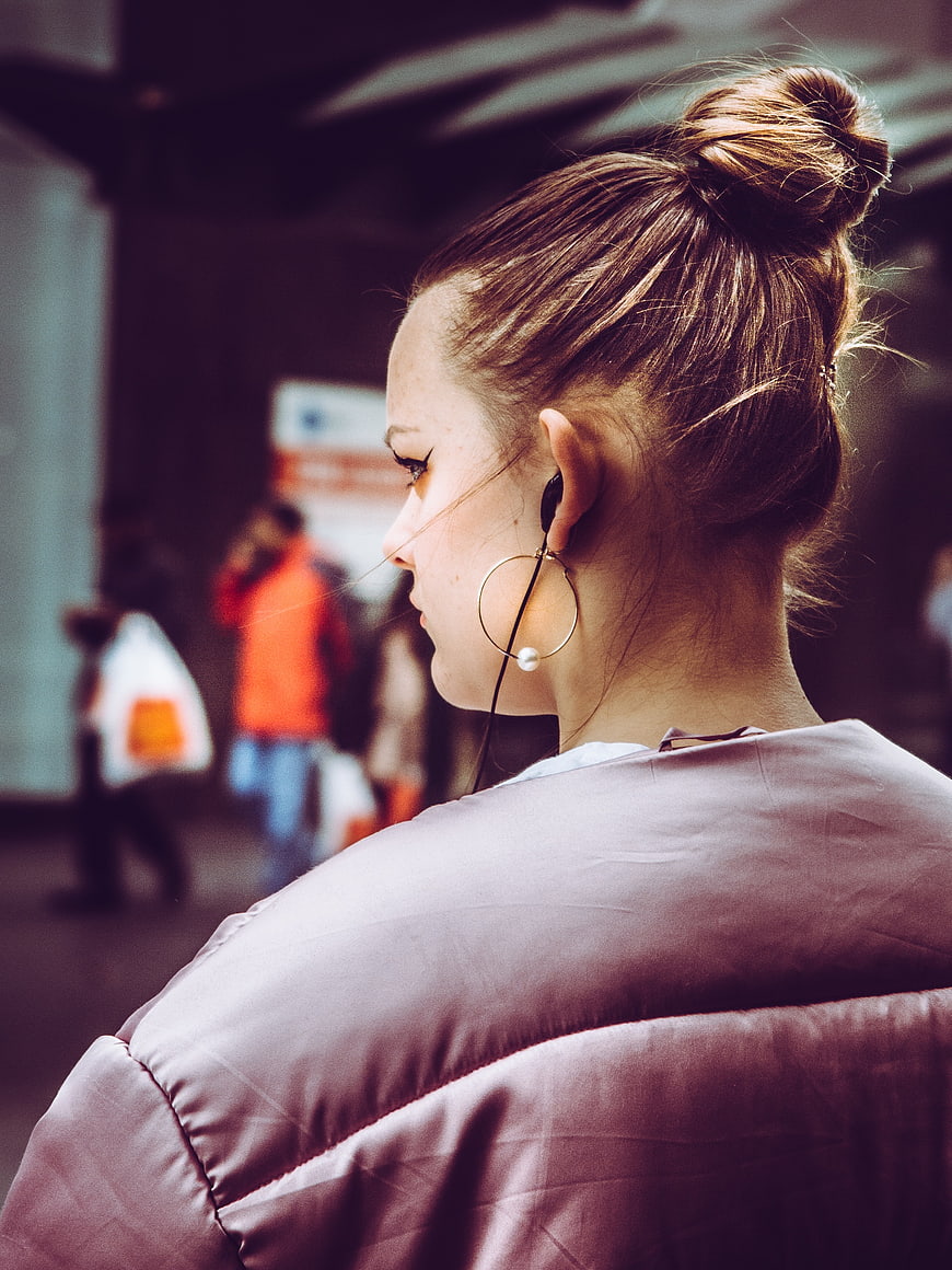 Woman with Bun and Earphones in Urban Setting