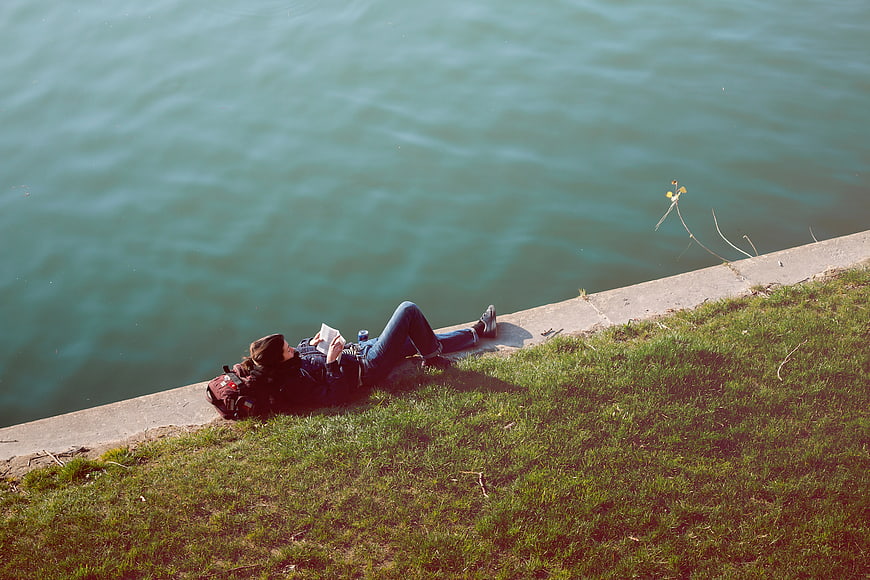 Man reading book while relaxing by the river