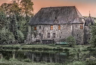Historic Stone Castle by Pond with Dramatic Sunset Sky