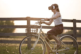 Girl Riding Bicycle with VR Headset at Sunset