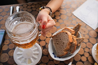 Woman's hand holding beer mug with bread slices