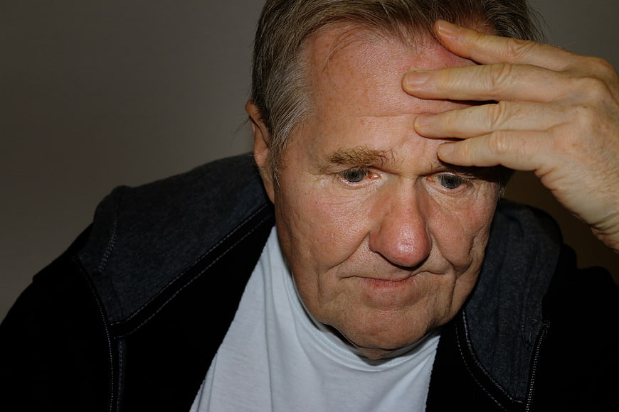 Senior man holding forehead in deep thought or worry