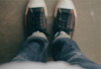 First-person view of sneakers and jeans on pavement