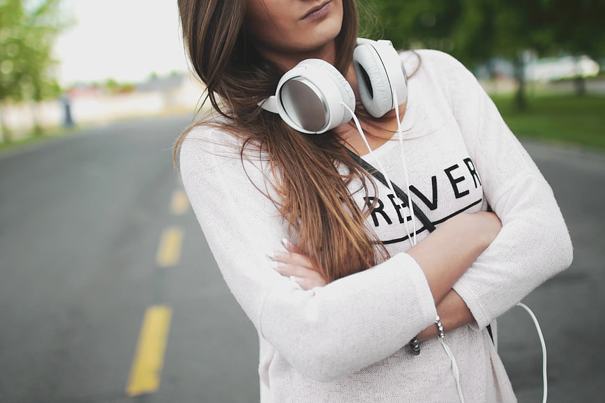 Woman with White Headphones Standing on Road