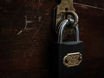Close-up of vintage padlock on dark wooden door