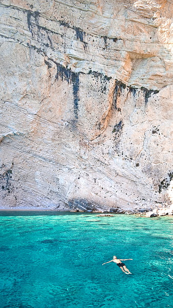 Man swimming in turquoise water near white cliffs