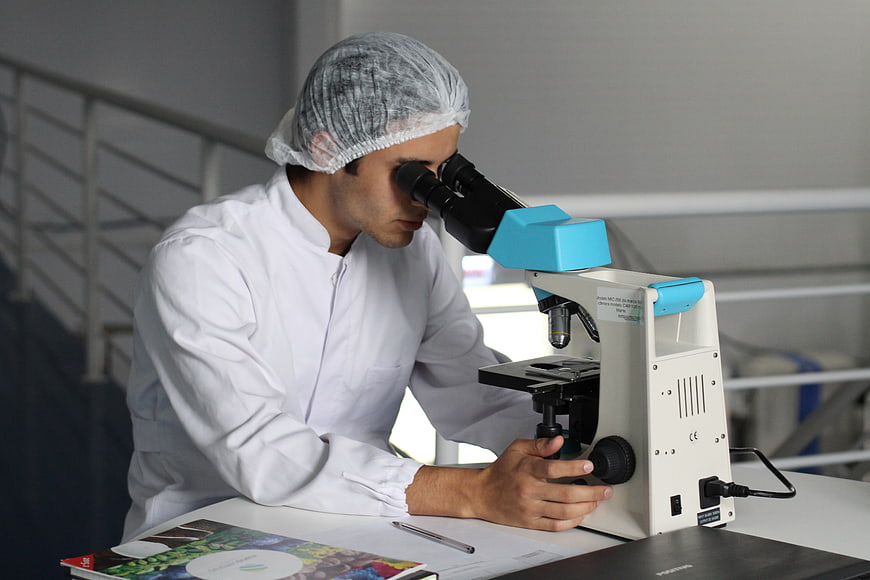 Scientist in Lab Coat Using Microscope in Laboratory
