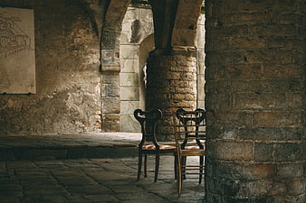 Antique wooden chairs in a rustic stone cloister