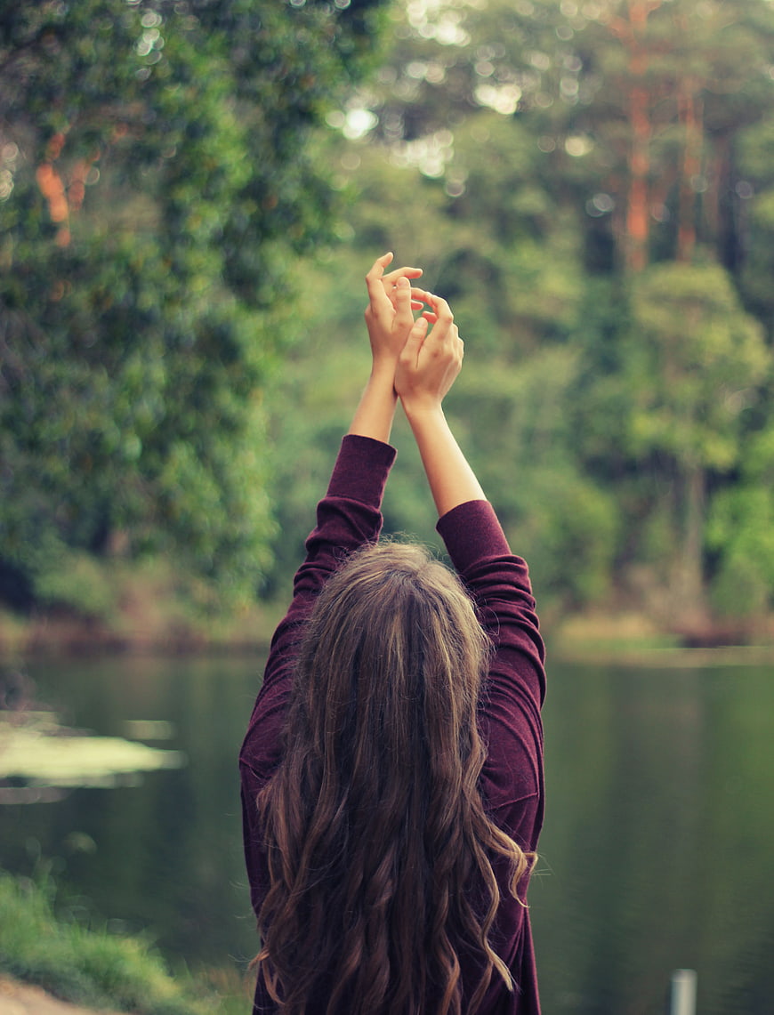 Woman stretching arms in nature by lake