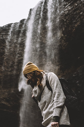 Woman in Beanie Standing Before Majestic Waterfall