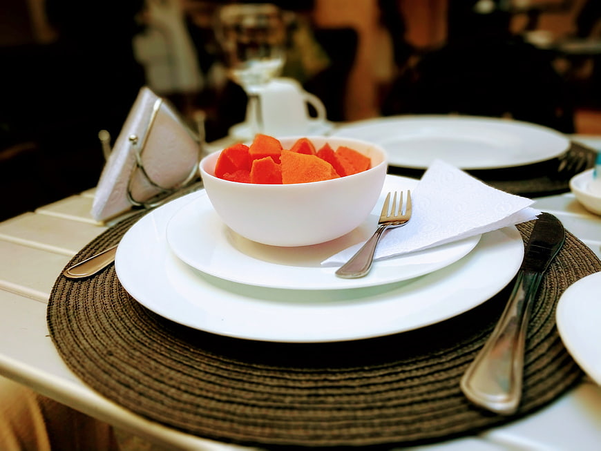 White bowl of fresh papaya on elegant restaurant table setting