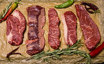 Raw beef steaks with rosemary and peppers on brown paper