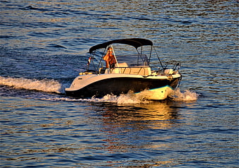 Man driving motorboat on ocean at golden hour