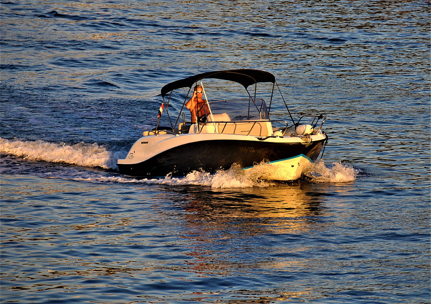 Man driving motorboat on ocean at golden hour