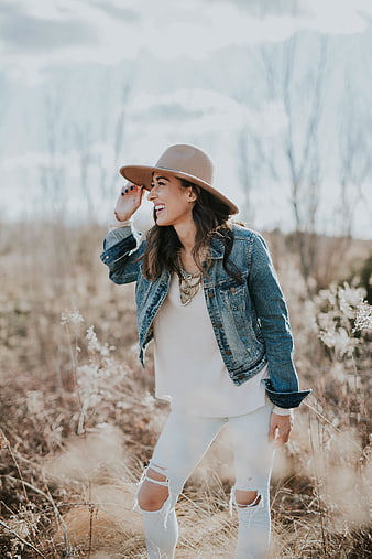 Happy woman in denim jacket and hat laughing in field