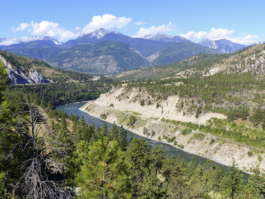 Scenic mountain river valley with railway tracks and pine forest