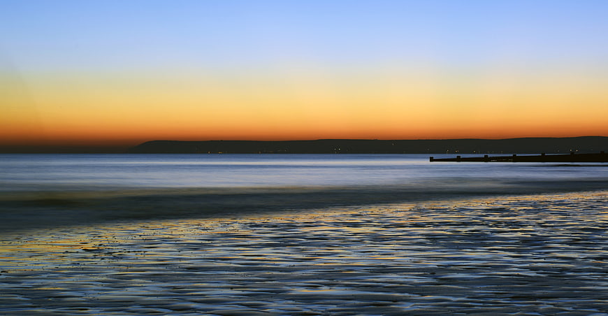 Serene Ocean Sunset With Distant Horizon And Calm Water