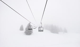 Empty ski lift chairs disappearing into whiteout fog