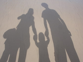 Family shadows holding hands on sandy beach