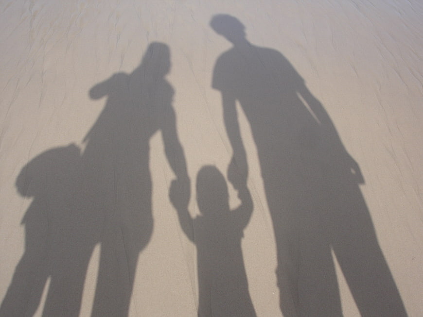 Family shadows holding hands on sandy beach