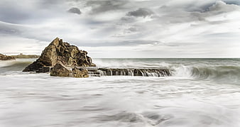 Dramatic long exposure seascape with rocky outcrop and misty waves