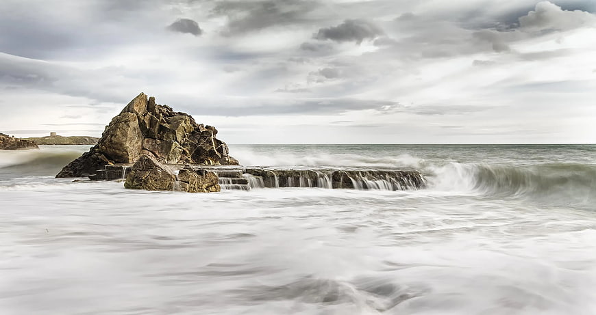 Dramatic long exposure seascape with rocky outcrop and misty waves