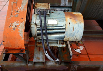 Rusty industrial electric motor on orange metal frame